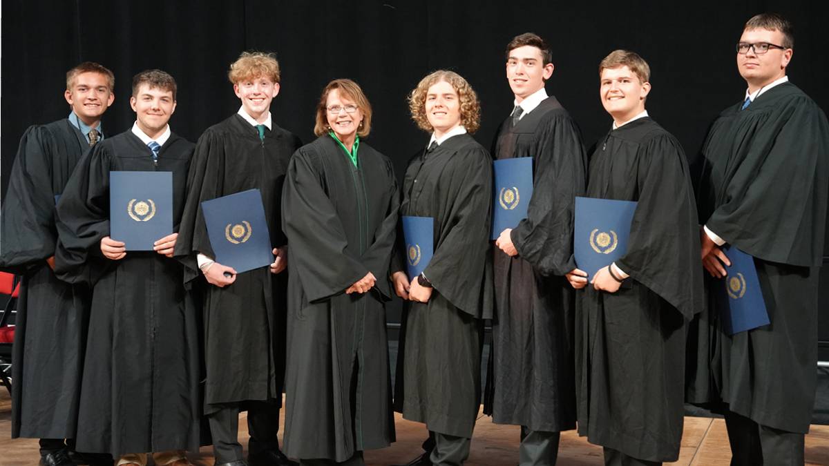 A group of robed delegates stand with the Chief Justice also in black robes