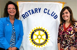 Image of a woman wearing a blue suit standing next to a woman wearing a flower print dress.