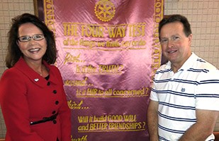 Image of a woman wearing a red dress standing next to a man wearing a blue and white striped polo.