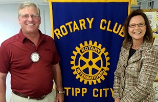 Image of a woman wearing a plaid suit standing next to a man wearing a red short sleeve dress shirt.