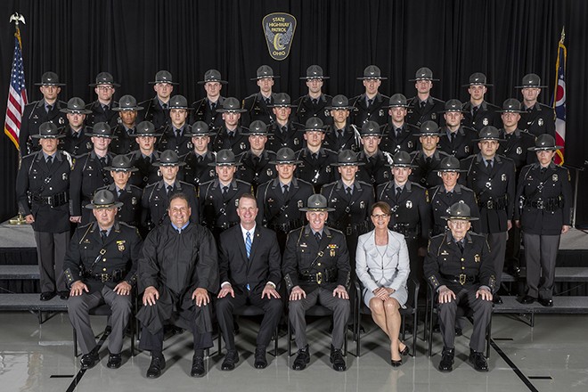 Five rows of Ohio State Highway Patrol cadets wearing uniforms. The first row has a male judge wearing a black judicial robe, a man wearing a black suit, and a woman wearing a light grey suit.