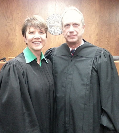 Image of a female judge wearing a black judicial robe and green blouse standing next to a male judge wearing a black judicial robe.