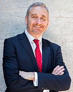 Image of a man wearing a blue suit and red tie.